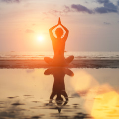 Woman meditating in a yoga pose on the beach
