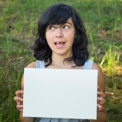 Funny young girl holding a white banner in hands, outdoors.