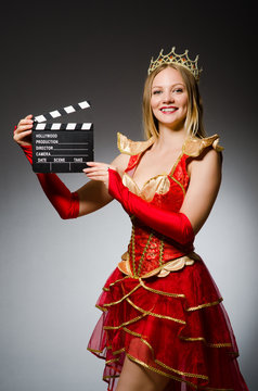 Queen in red dress with movie clapboard