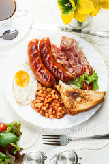Full English breakfast with bacon, sausage, fried egg and baked