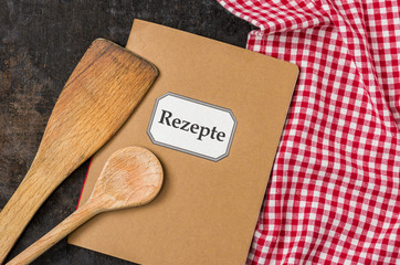 Rezeptbuch mit Kochlöffeln auf einem rot karierten Tischtuch