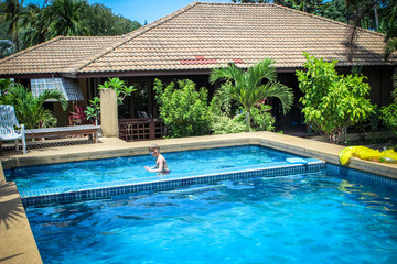 boy swims into blue swimming pool in resort. Koh Samui