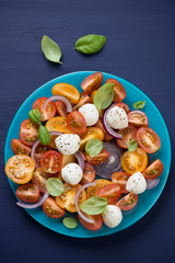 Salad with various types of tomatoes, cheese, onion and basil