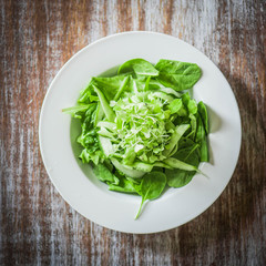 Salas with spinach,cucumber and microgreens on wooden background