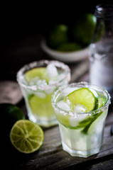 Water with ice and limes on rustic background