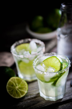 Water with ice and limes on rustic background