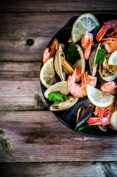 Mix of mussels,clams and shrimps on wooden background