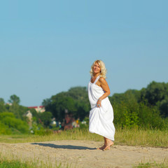 Fototapeta na wymiar Mature beautiful blonde walks on the sandy road 