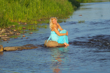 mature beautiful blonde in vintage dress having fun in the sea. 