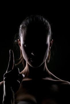 woman with the face in the shadow pointing a finger upwards