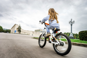 Cute little girl riding fast by bicycle