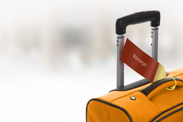 Voyage. Orange suitcase with label at airport.