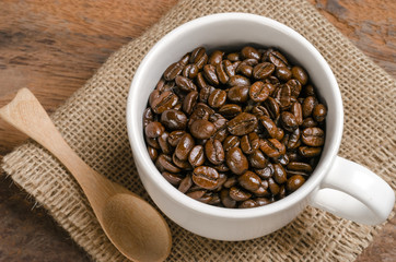 coffee beans in the white cup on sack with spoon