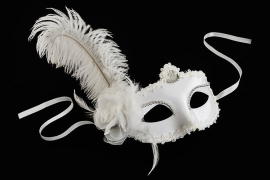 White carnival mask with feather on black background