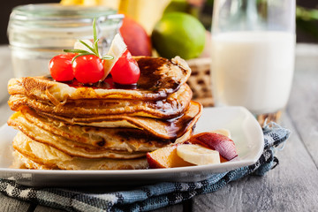Pancakes with chocolate sauce fruit and glass of milk