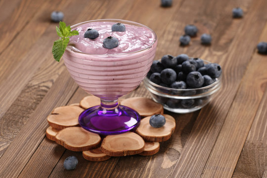 yogurt with blueberries in a glass bowl and blueberries in a gla