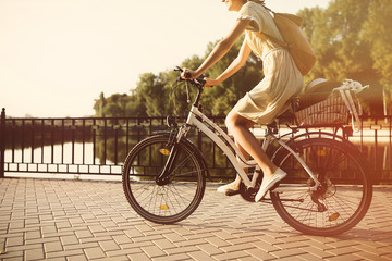 Fototapeta na wymiar Girl riding a bicycle in park near the lake. Lightleak effect an