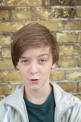 portrait of a smiling teenager boy in front of a brick wall