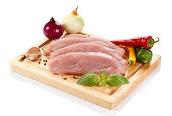 Raw turkey fillets on cutting board and vegetables