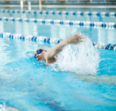 Young girl in goggles swimming front crawl stroke style