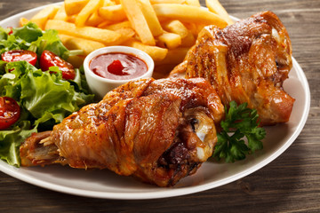 Grilled turkey legs with French fries and vegetables