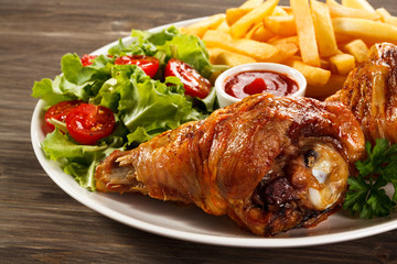 Grilled turkey legs with French fries and vegetables