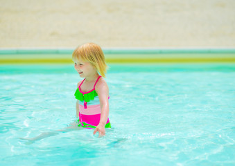 Fototapeta na wymiar Baby girl playing in swimming pool