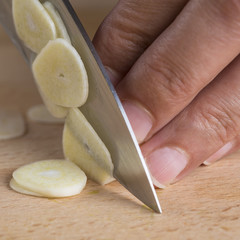 Fototapeta na wymiar Cocinero cortando ajos laminados con el cuchillo en la cocina