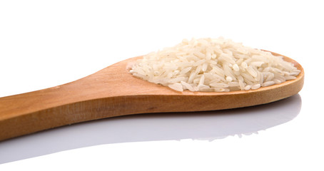 Raw and uncooked rice in wooden spoon over white background