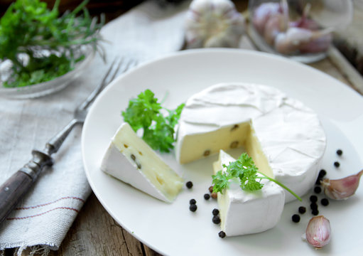 Camembert cheese with herbs on a white plate for appetizer