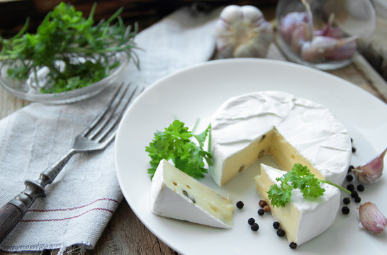 French cheese with fresh herbs and spices on a white plate