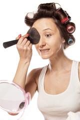 happy housewife with curlers to apply makeup on her face