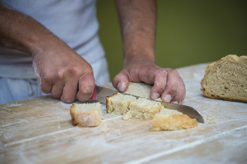 Panadero cortando un trozo de pan recién hecho en el obrador