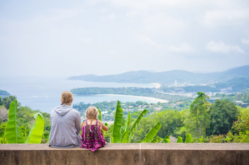 Mother and daughter look around from mountain view point on trop