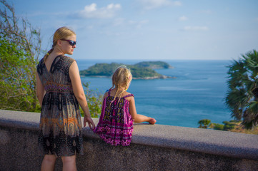 Mother and daughter at side of tropical island view piont