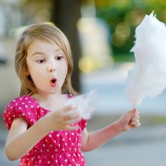 Adorable little girl eating candy-floss outdoors © MNStudio