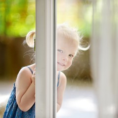 Cute little toddler girl peeking into a window © MNStudio