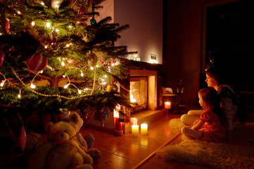 Young mother and her daughter by a fireplace