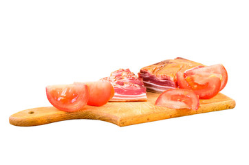 Raw smoked bacon on a wooden plate with tomatoes