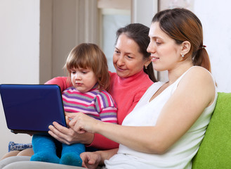 Fototapeta na wymiar Happy women of three generations with netbook