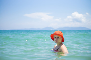 Young woman in orange hat swim in tropical ocean