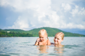 Fototapeta na wymiar Young mother and daughter have fun swim on island in tropical oc