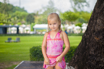 Adorable girl take shower under tree at tropical beach resort