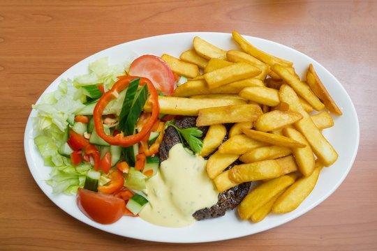 Patty steak served with salad french fries and bearnaise sauce