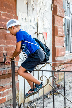 Child Boy Climbing Over Metal Fence In A Street, Side View