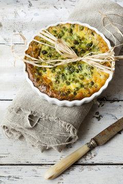 vegetables french quiche with peas on baking dish with knife
