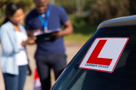 learner driver and instructor behind a car