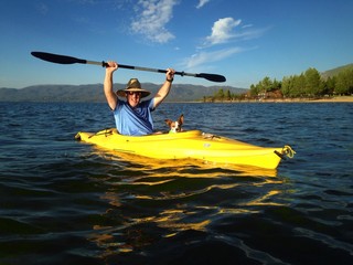 Athletic man kayaking on Lake Tahoe with dog.