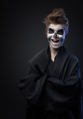 Obraz premium Teen with make-up of skull in black cloak laughs