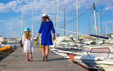 Young mother with little girl in the port enjoying sunny summer